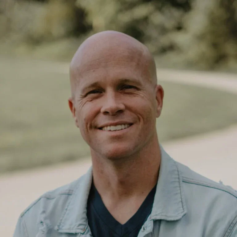 Bald man smiling outdoors, promoting church community and faith inspiration.