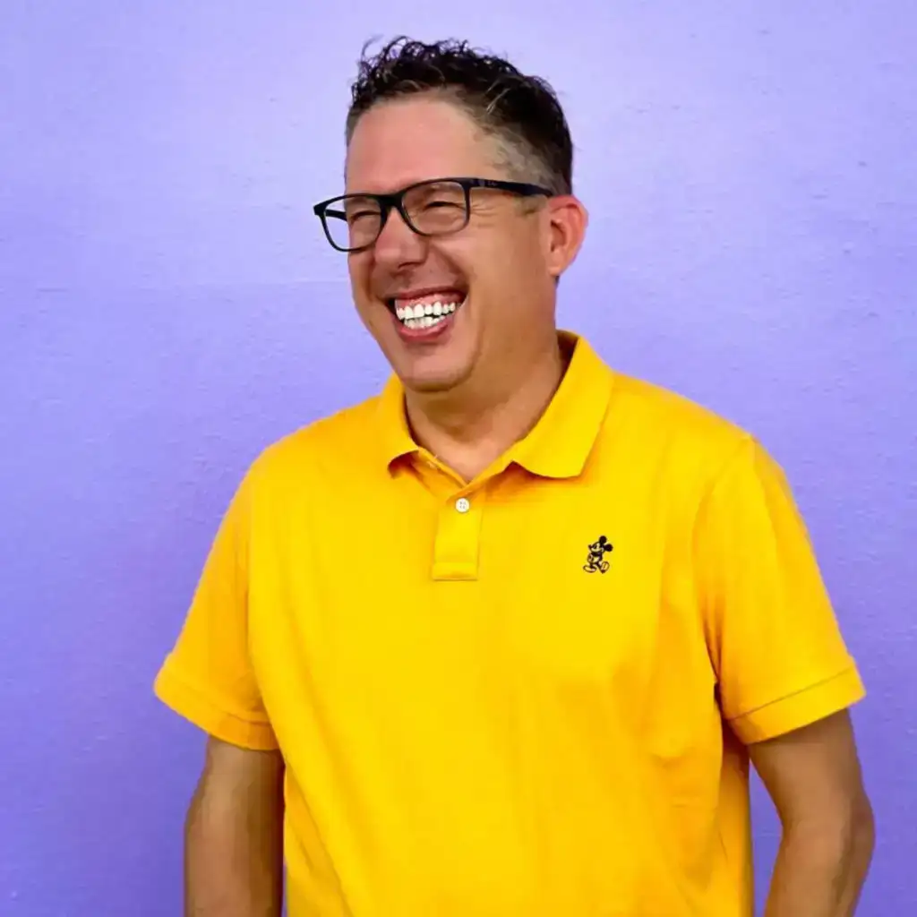 Happy man in yellow shirt laughing standing against purple wall, vibrant church community, joyful faith, modern church gatherings, positive church culture.